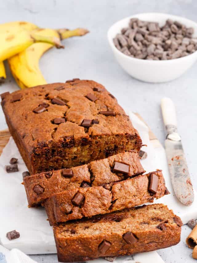cutting board lined with parchment paper and slices of dark chocolate banana bread.