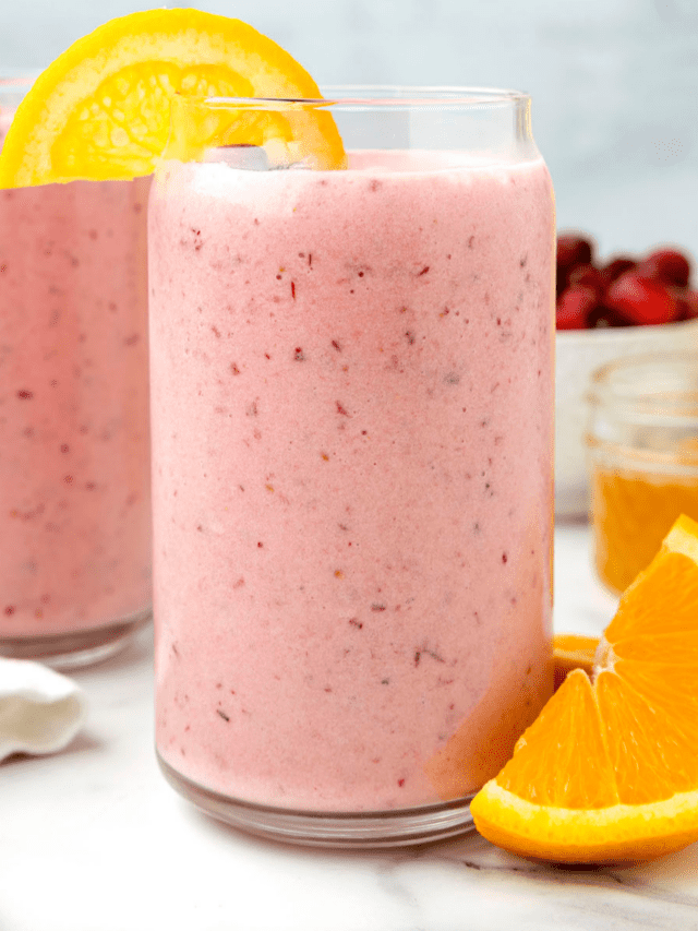 two glasses with the cranberry smoothie and orange wedges.