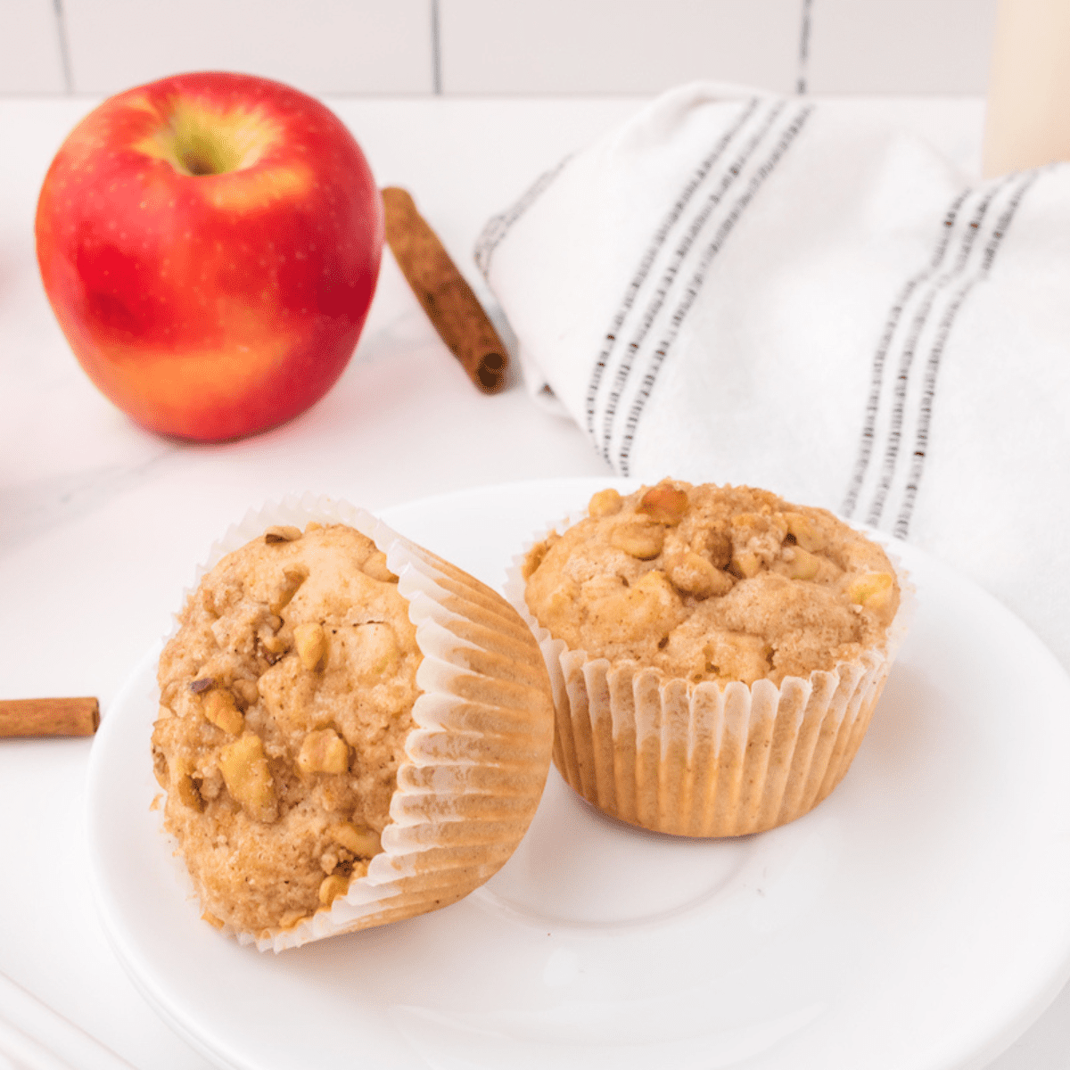 two apple crumble muffins on a white plate.