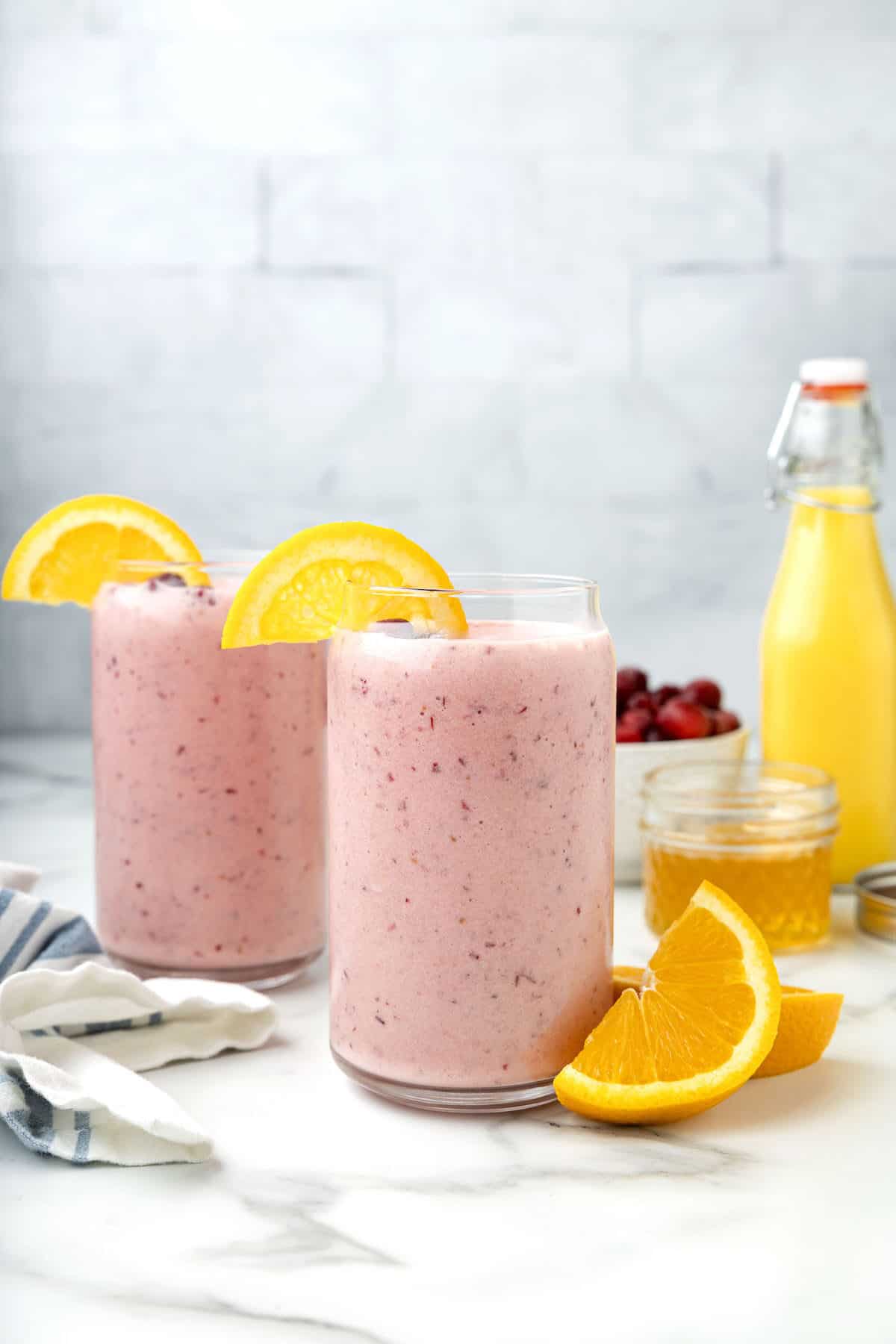 two classes of the cranberry smoothie with wedges of oranges