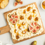 wooden board with butter spread, goat cheese, figs, and fig spread.