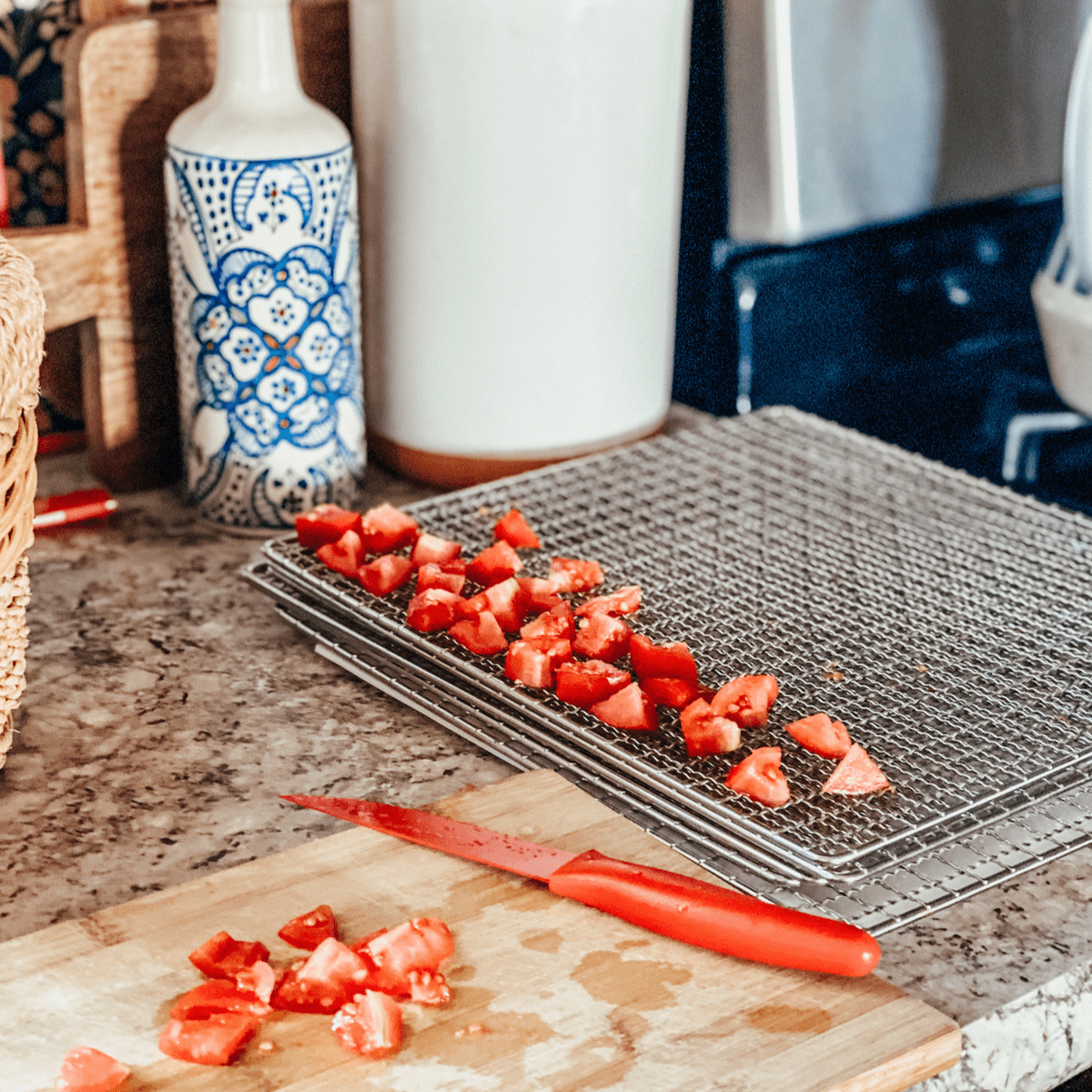 slicing and chopping fresh tomatoes and adding them to dehydrating trays.