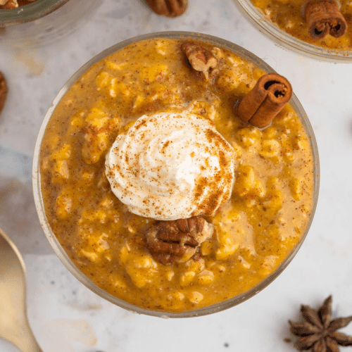 closeup view of the healthy pumpkin pie overnight oats in a bowl with whipped cream on top.
