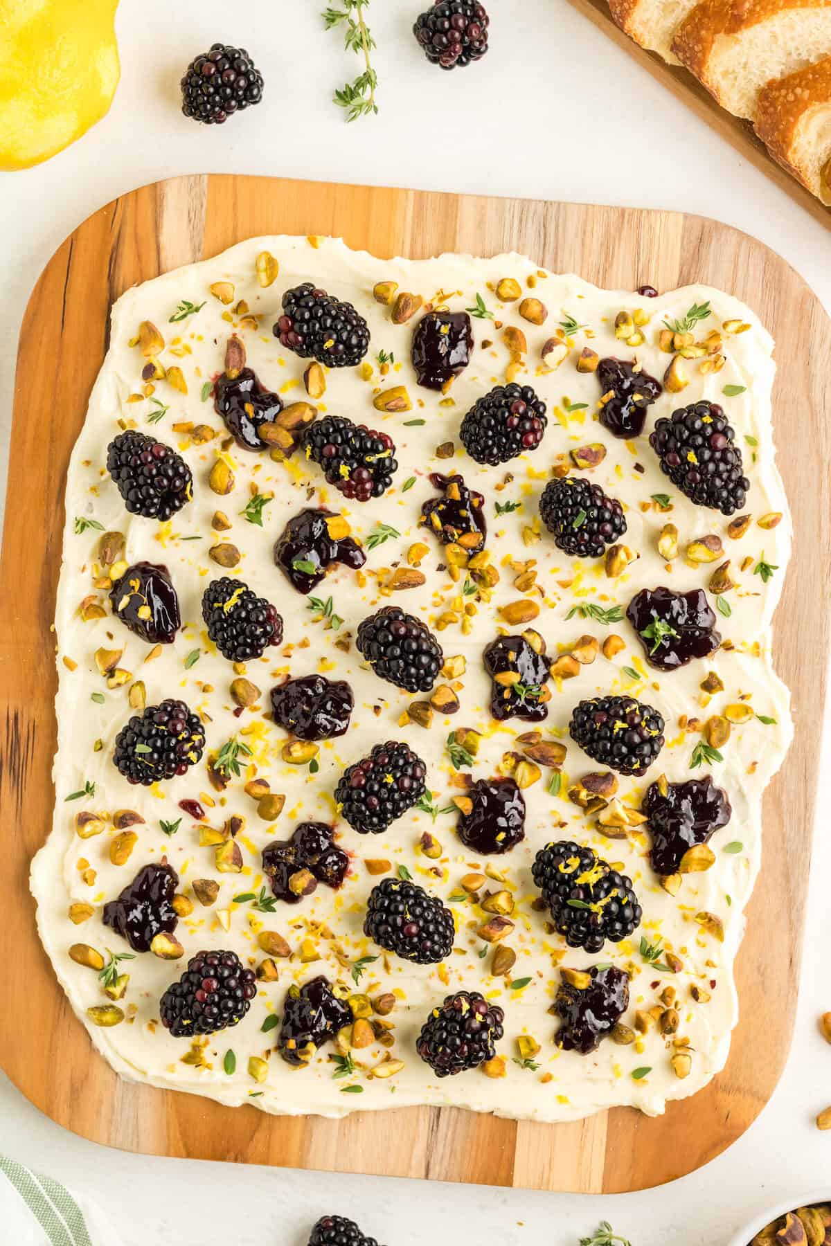 butter board with blackberries and pistachios with crusty bread to the side.