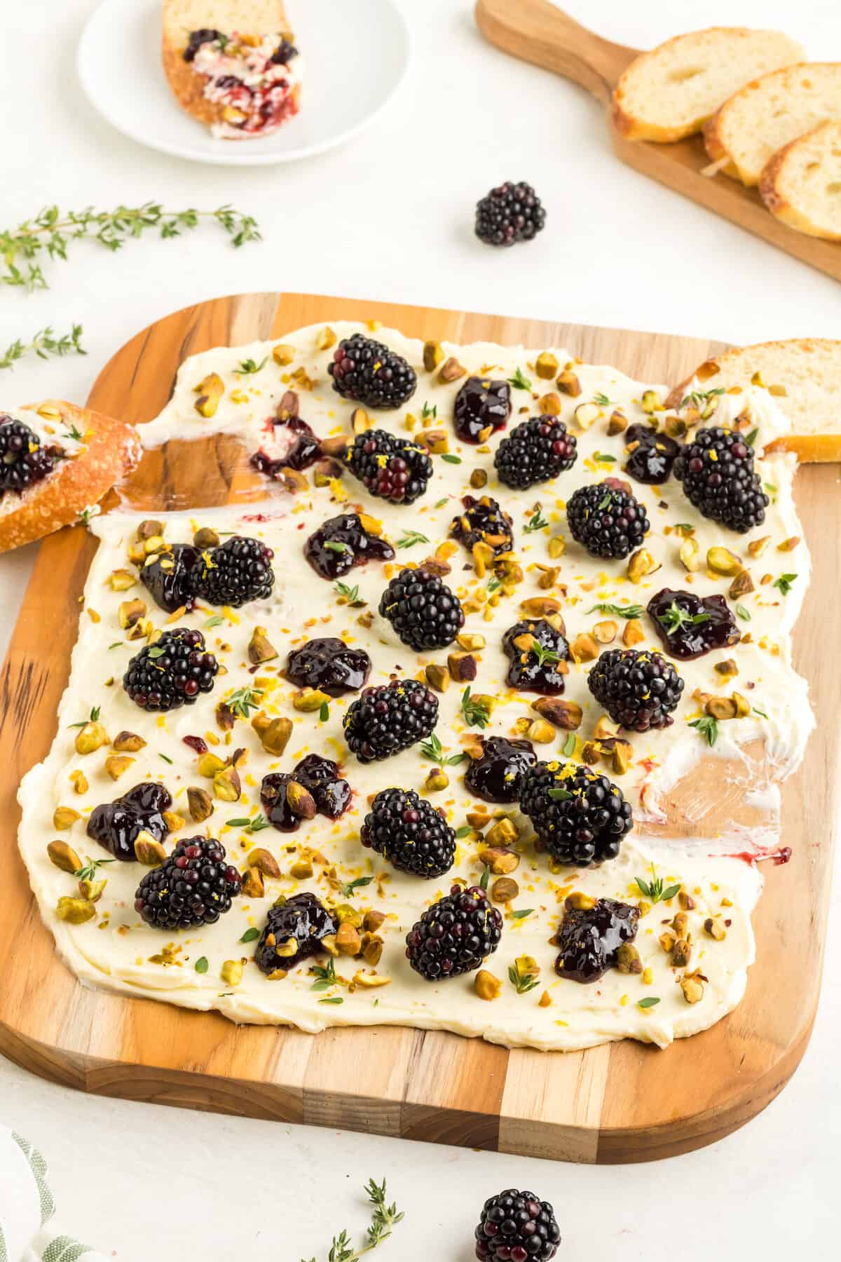 wooden serving board with butter, pistachios and blackberries.