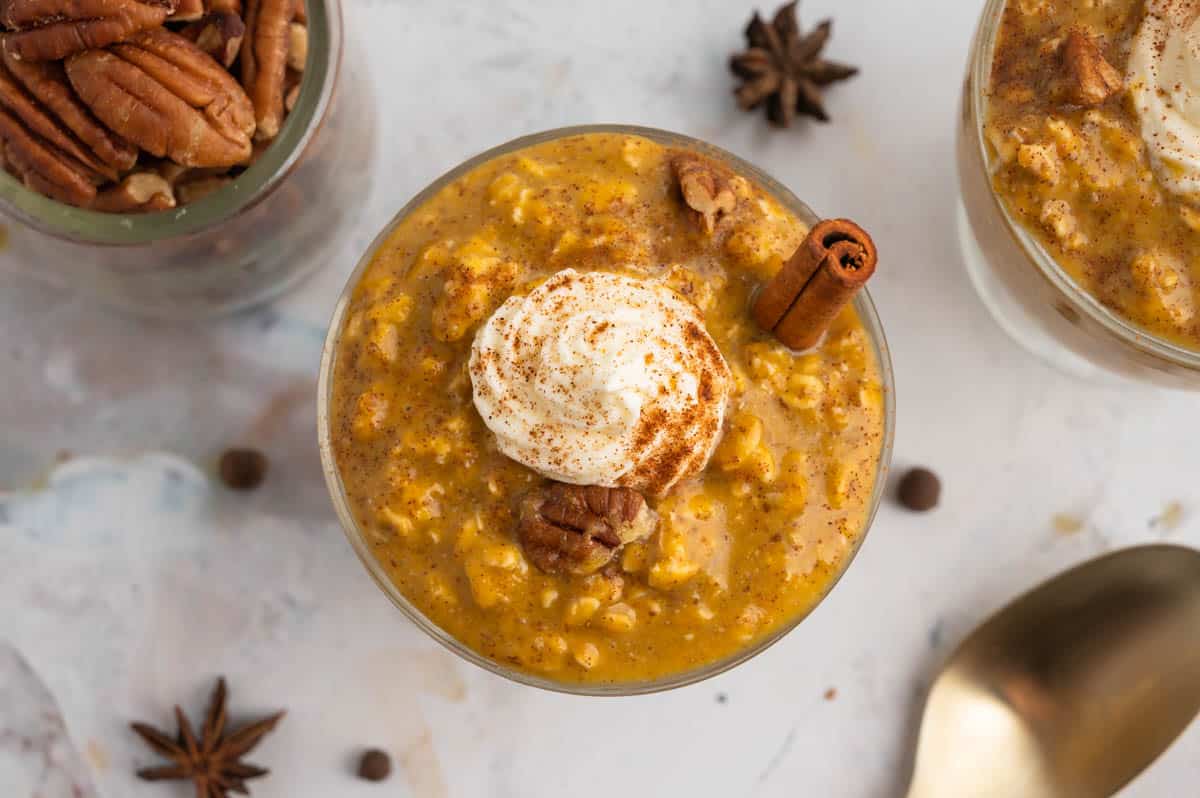 pumpkin pie overnight oats in a small bowl with a dollop of whipped cream on top.
