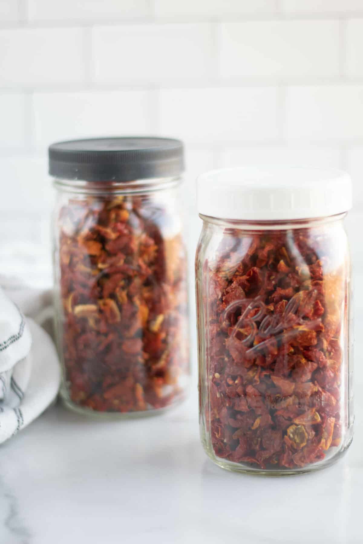 two mason jars filled with dehydrated tomatoes.