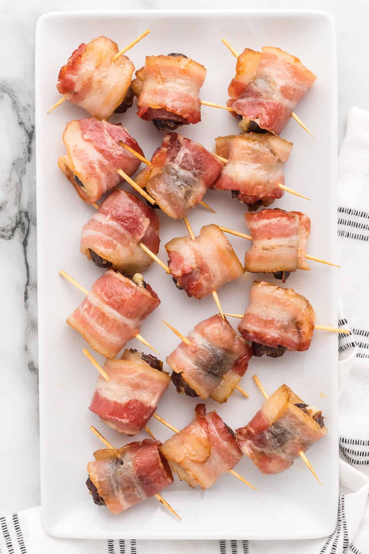 white platter with finished bacon wrapped dates. 