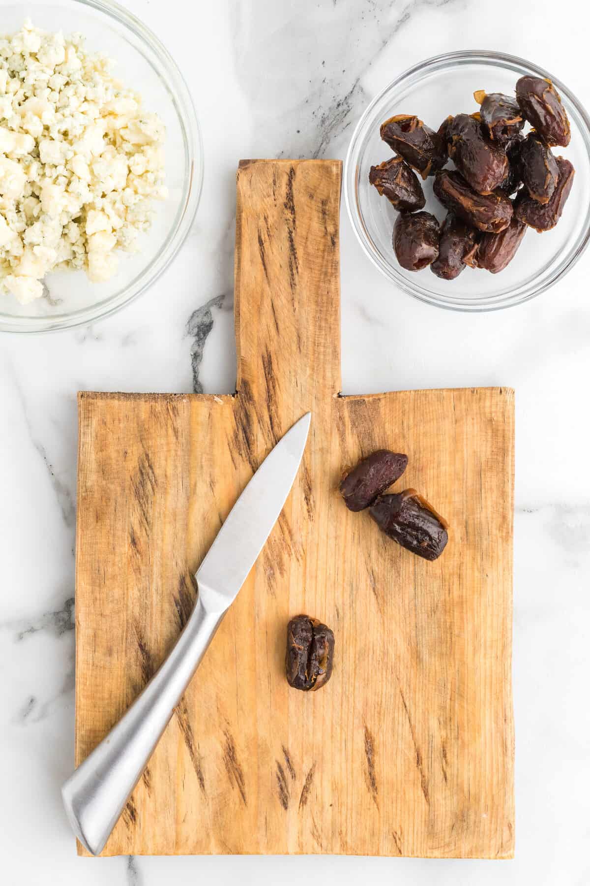 slicing the dates on a wooden cutting board.
