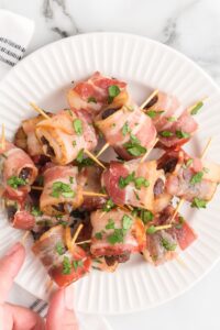 white plate with bacon wrapped dates and toothpicks inserted in the middle.