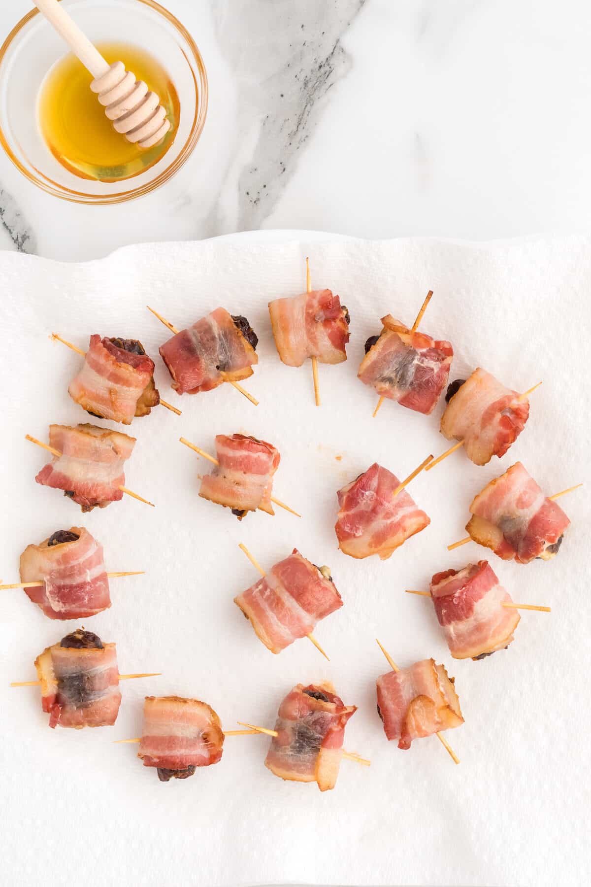 bacon wrapped dates on a paper towel.