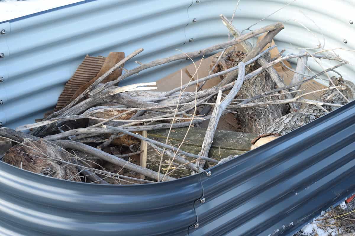 cardboard, logs, and sticks in the bottom of the raised beds.