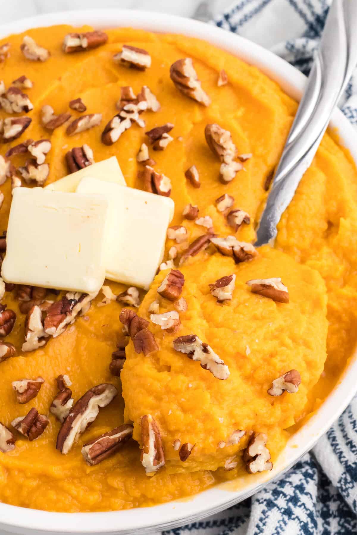 spoonful of mashed sweet potato over a large serving bowl.
