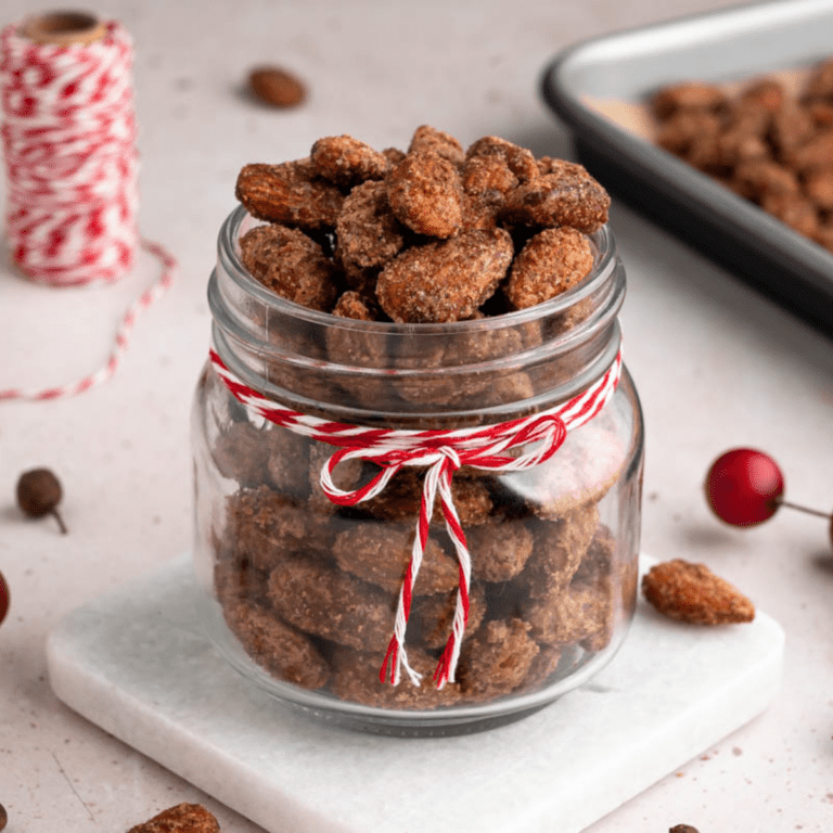small mason jar of holiday maple spiced almonds with a red and white ribbon tied around the top.
