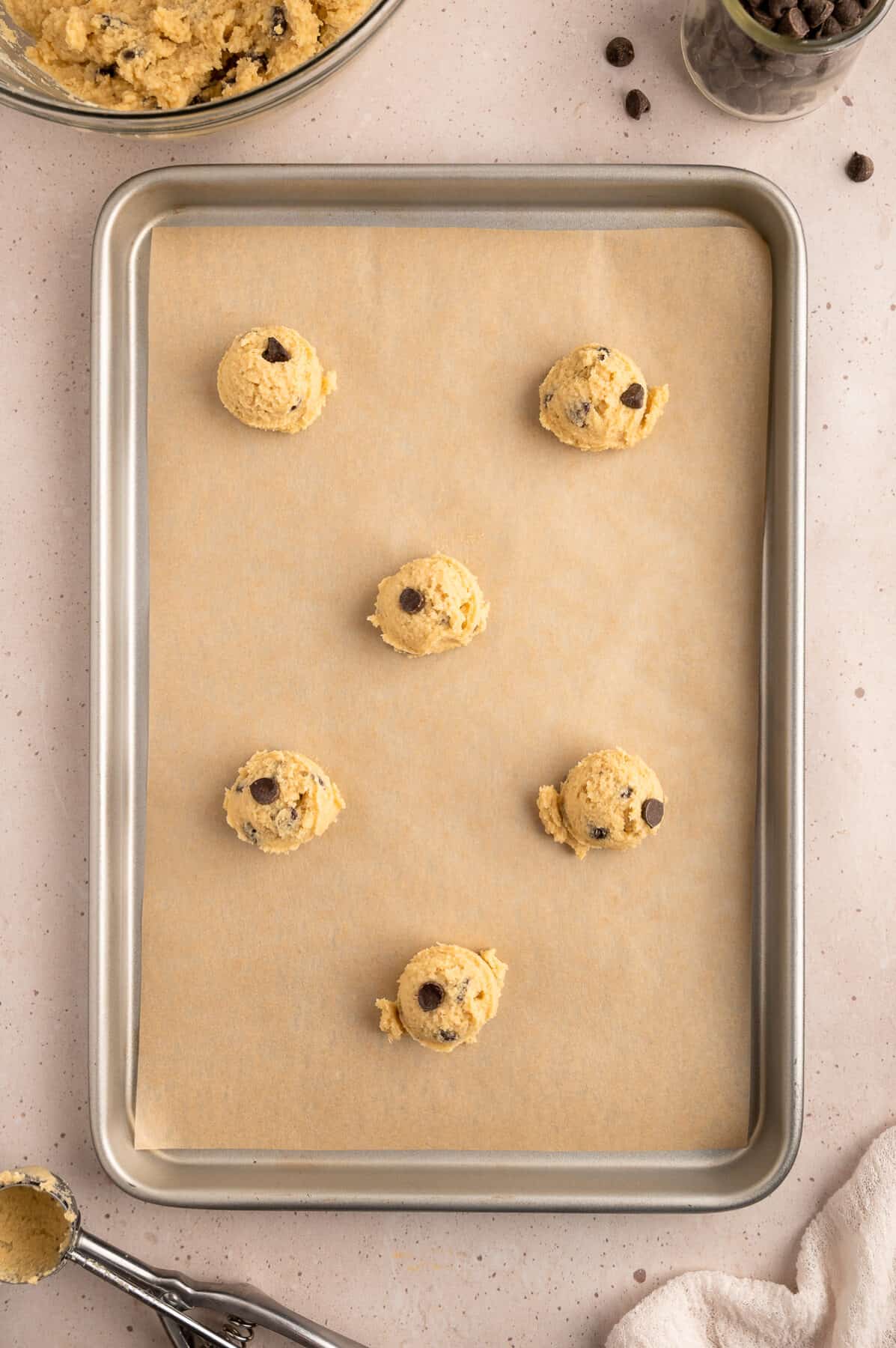 cookie dough balls on a parchment paper lined baking sheet. 