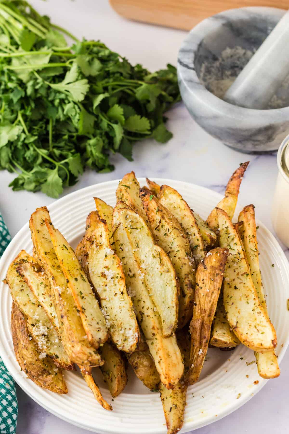 garlic and herb roasted potato wedges on a white plate.