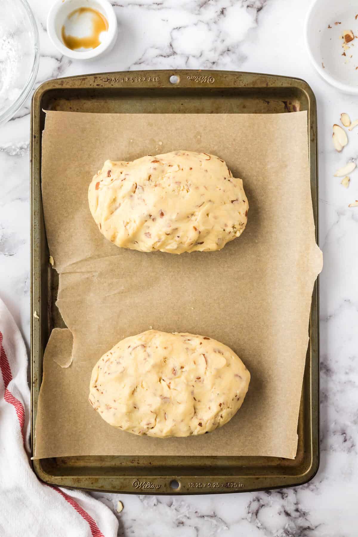 biscotti dough divided in half and on a parchment paper lined baking sheet.