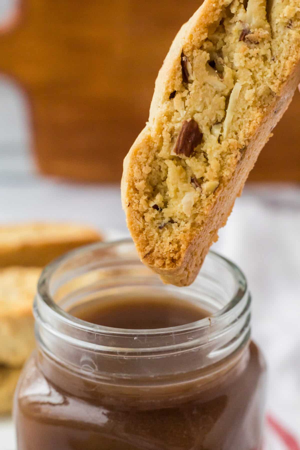 dunking an almond biscotti into a cup of coffee.