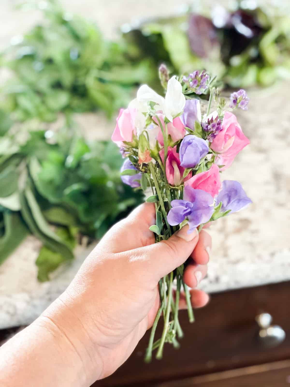 holding a small bouquet of sweet pea flowers. 