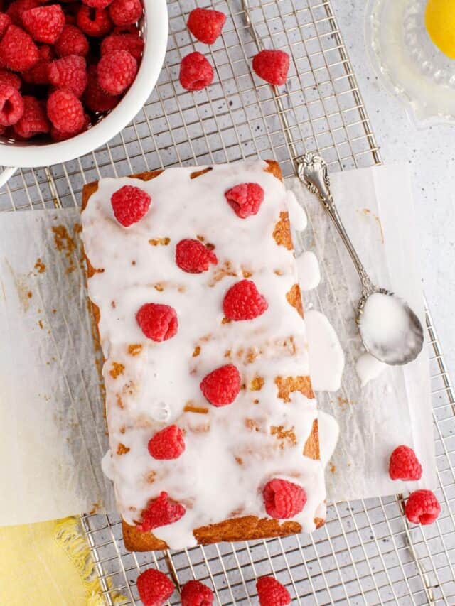 lemon raspberry bread on a wire cooling rack with a spoon and drizzle of icing.