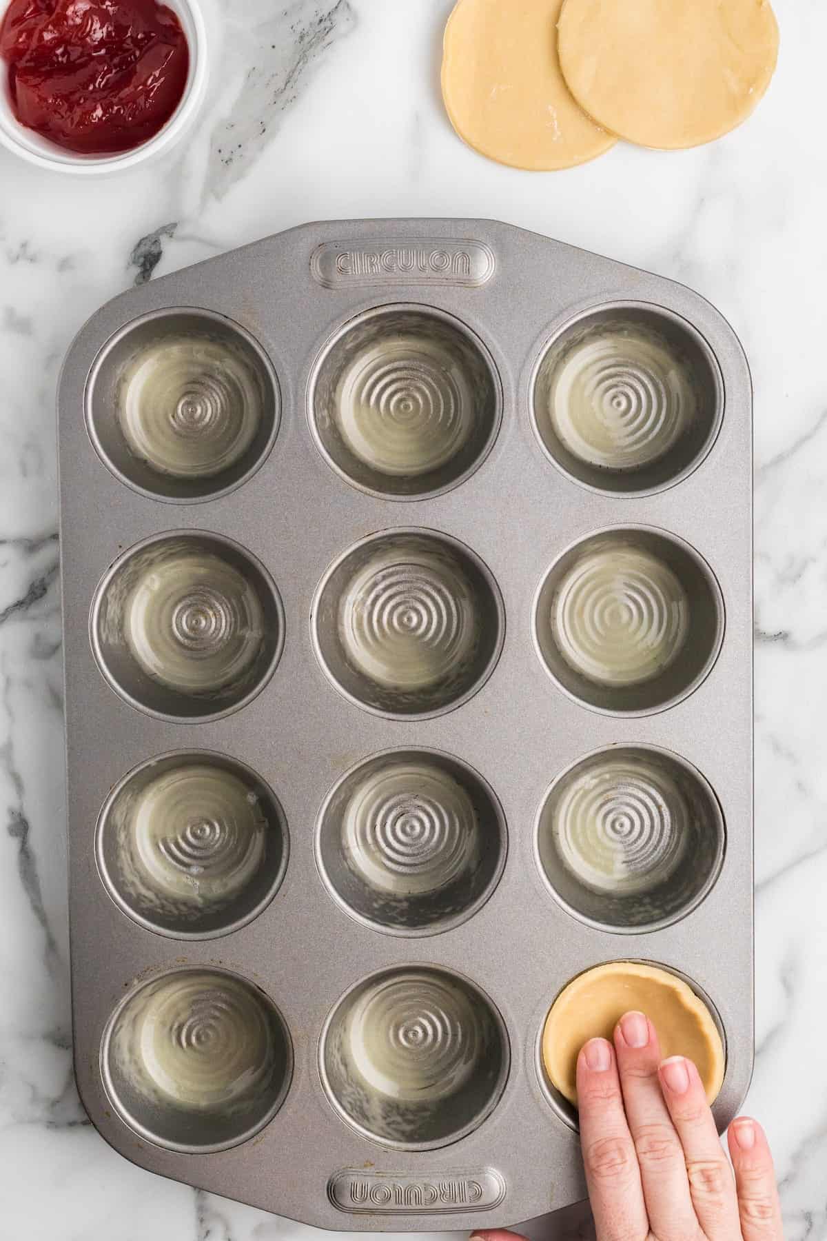 filling the muffin tins with the pastry dough.