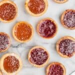 variety of mini jam tarts spread on countertop.