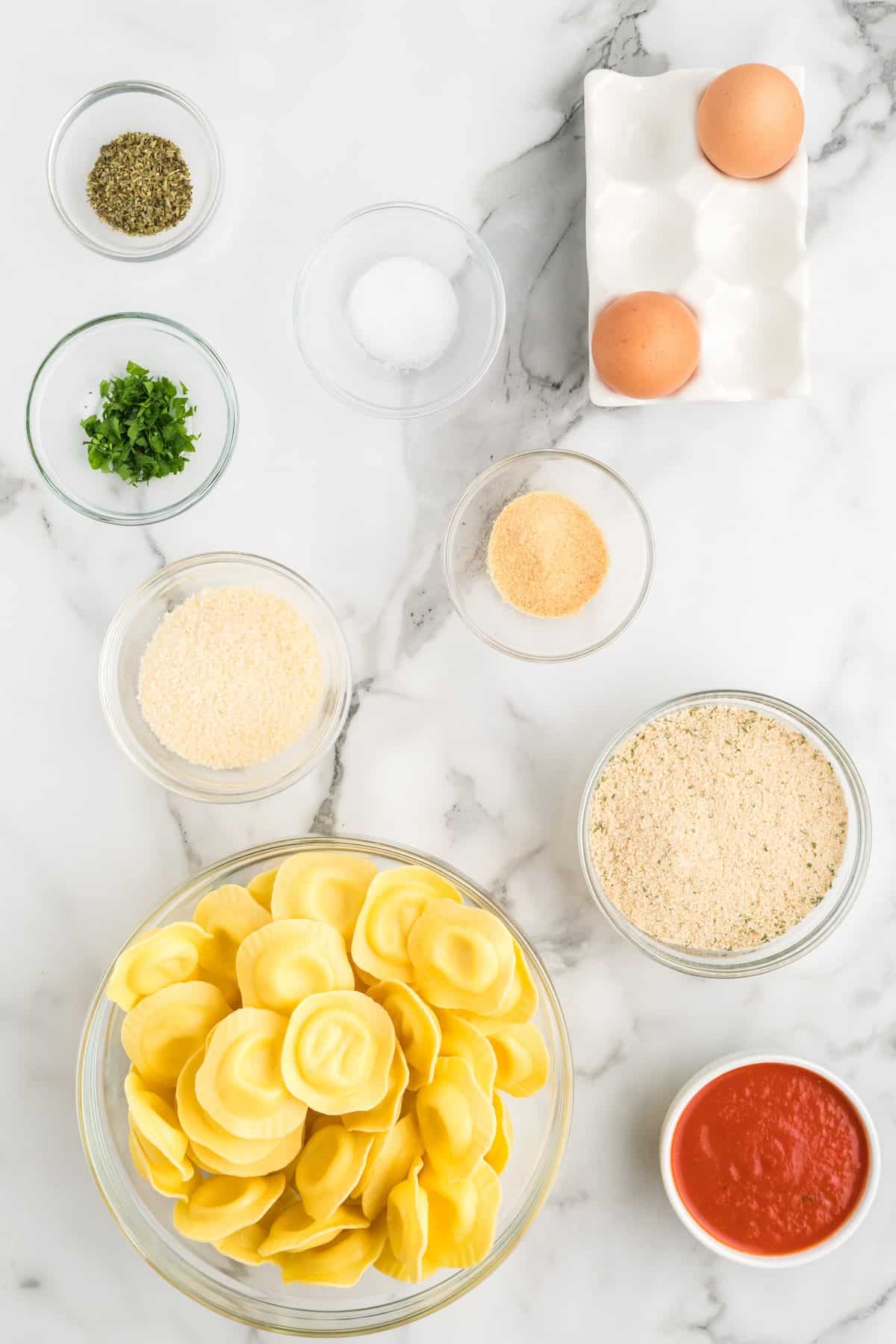 ingredients for the air fryer ravioli in small glass bowls on the countertop.