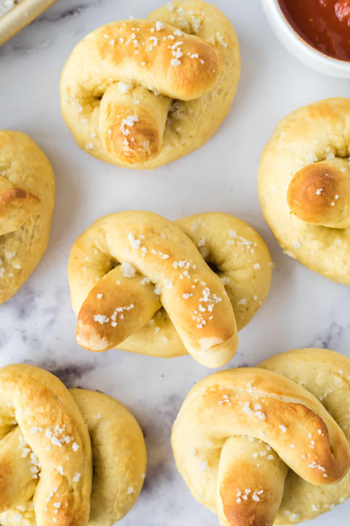 baked fresh soft homemade pretzels on a white countertop.