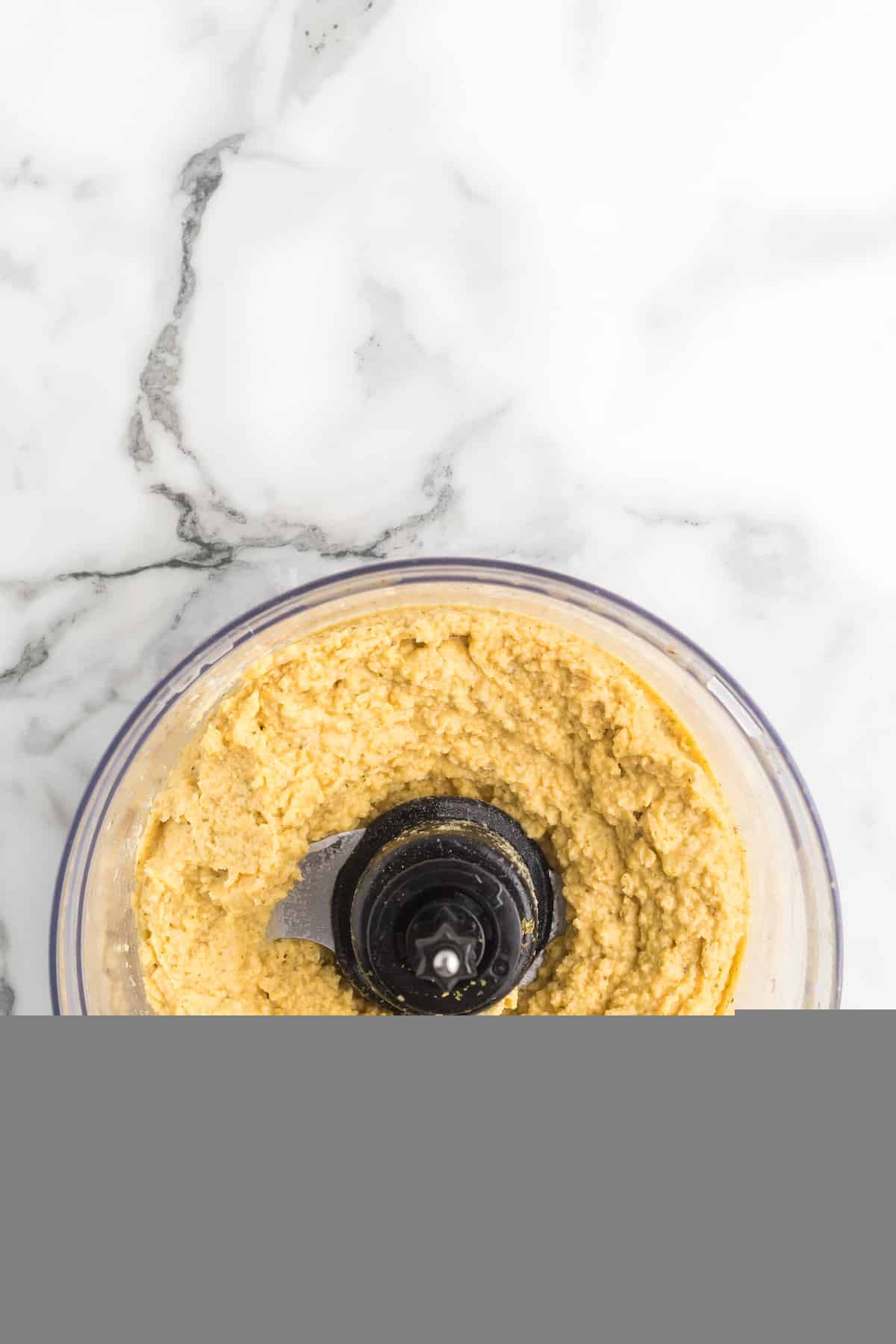 fresh garlic hummus blended in the bowl of the food processor.