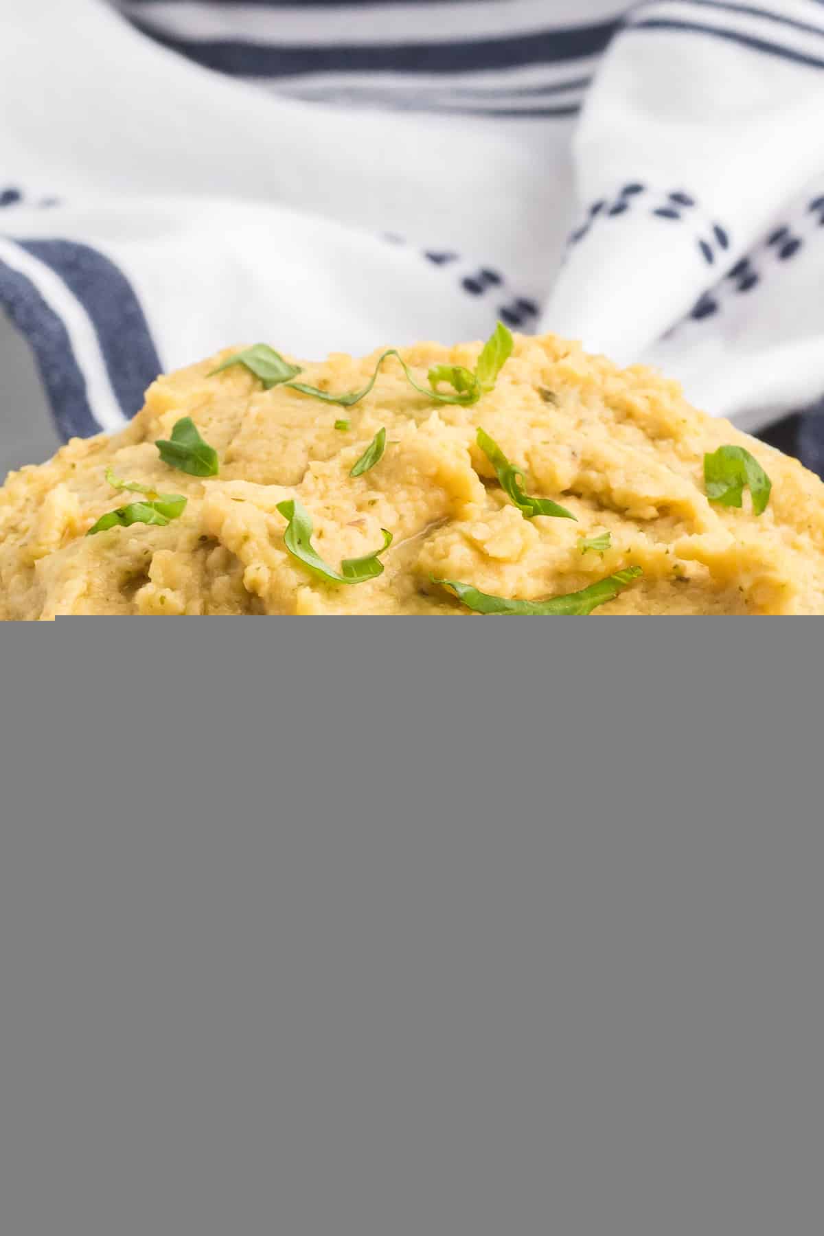 garlic hummus in a little white bowl and topped with chopped basil.
