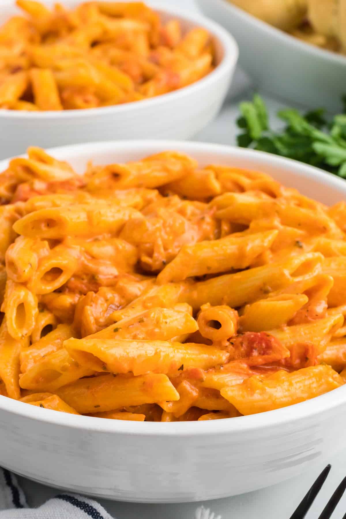 serving bowls with creamy pomodoro sauce over penne pasta.