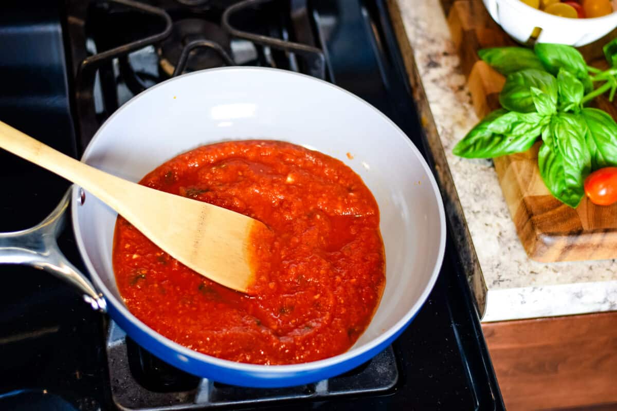 caraway pan with pasta sauce and wooden spoon.