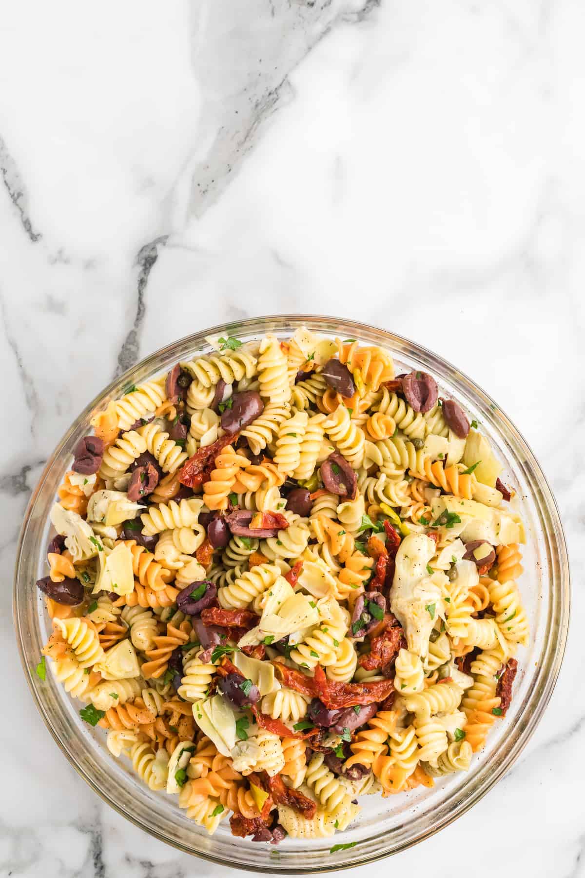 finished pasta salad in a large glass mixing bowl.