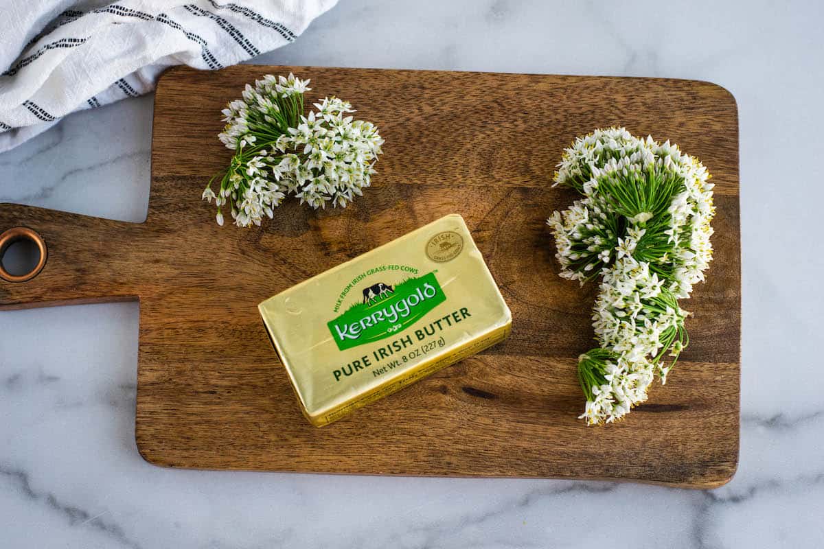 freshly harvested chive blossoms with kerrygold butter on a wooden board. 