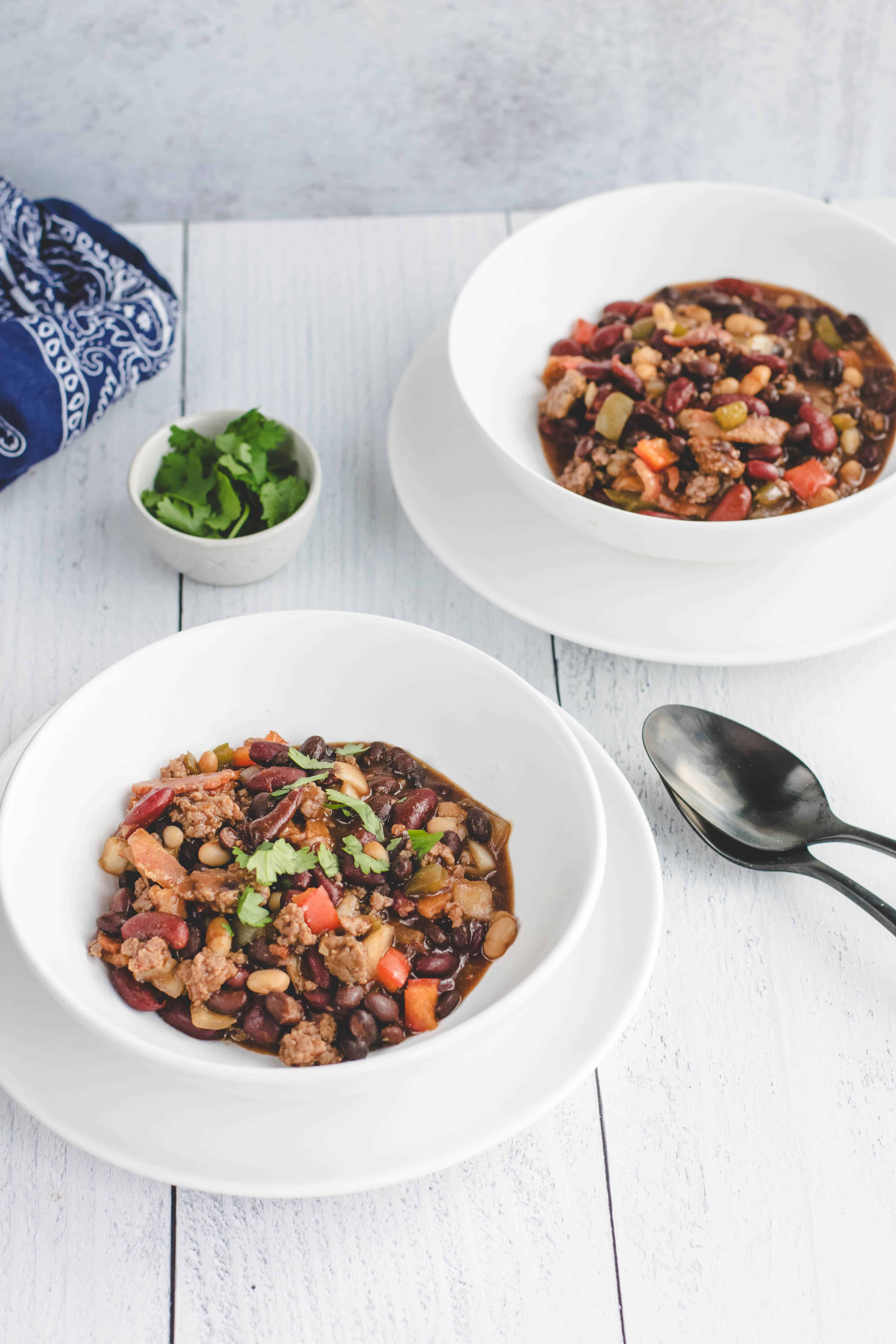 two white bowls with cowboy beans and small bowl of cilantro.