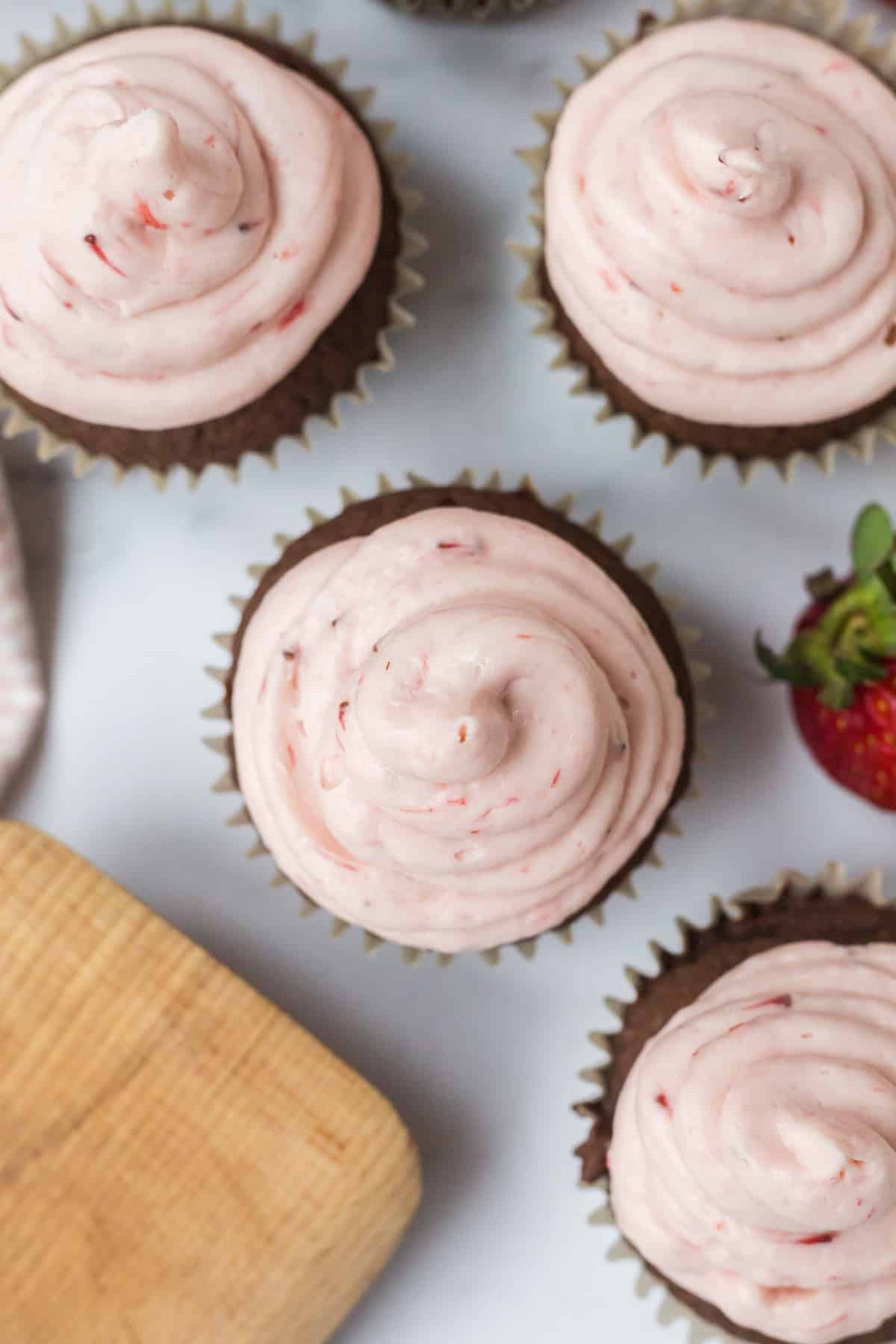 nutella chocolate muffins with strawberry frosting on top and resting on the countertop. 
