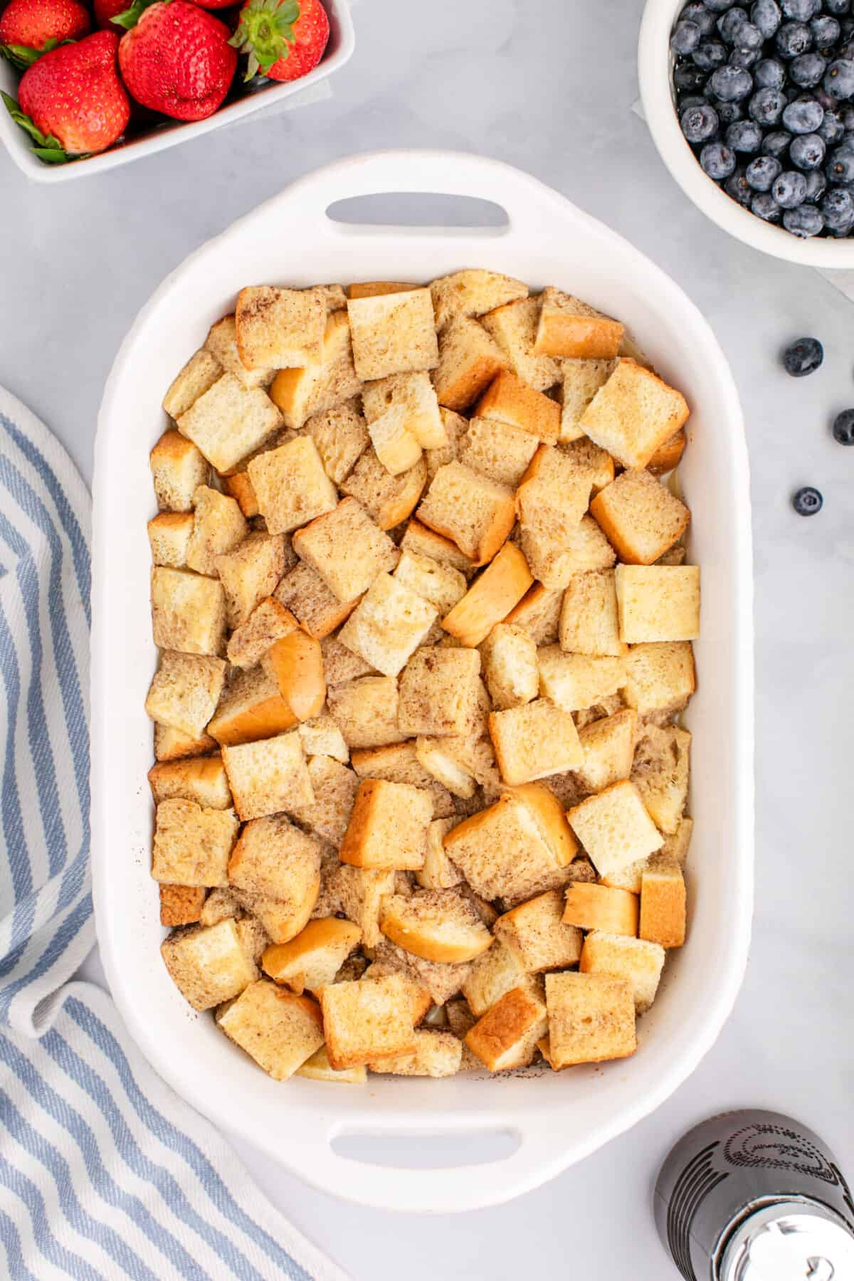 cubes of bread in a baking dish soaking up the wet ingredients. 