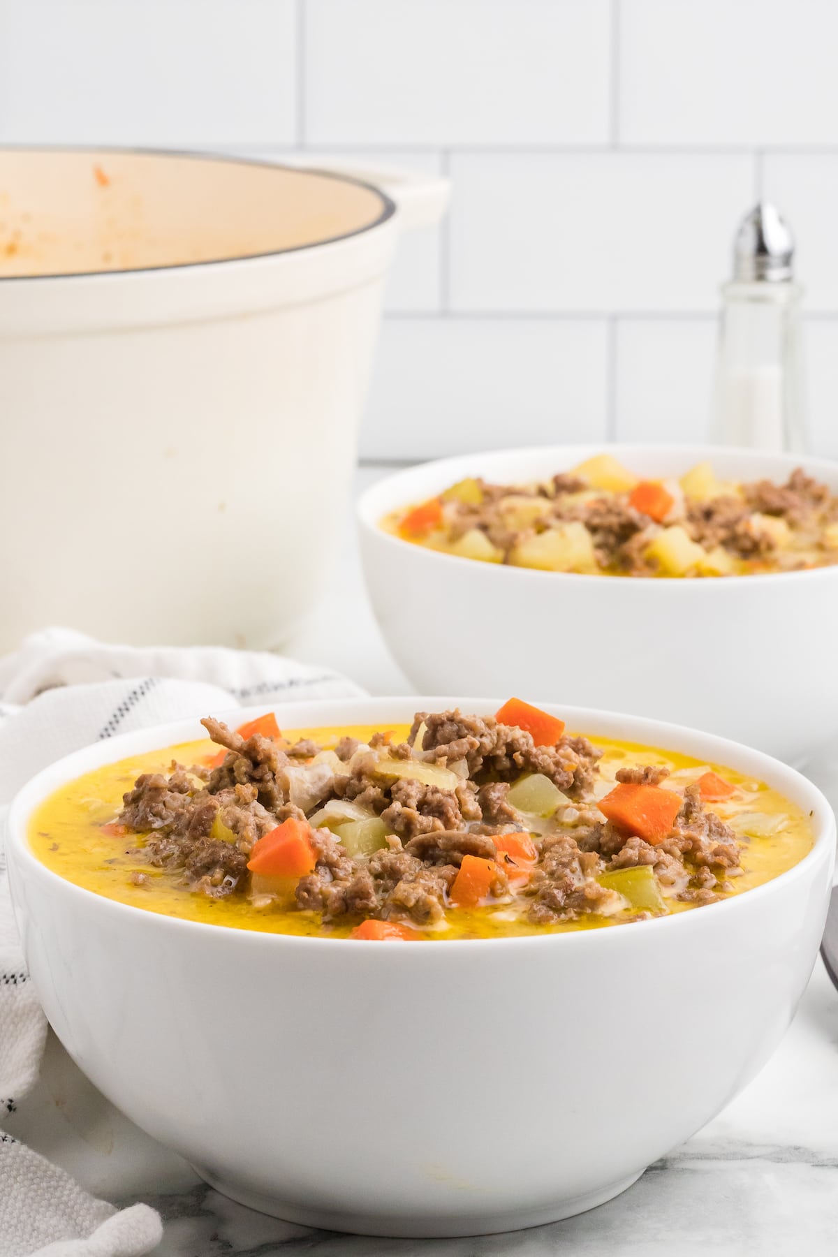 white soup bowls filled with finished cheeseburger soup. 