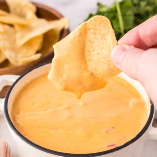 dipping a chip in the queso sauce.