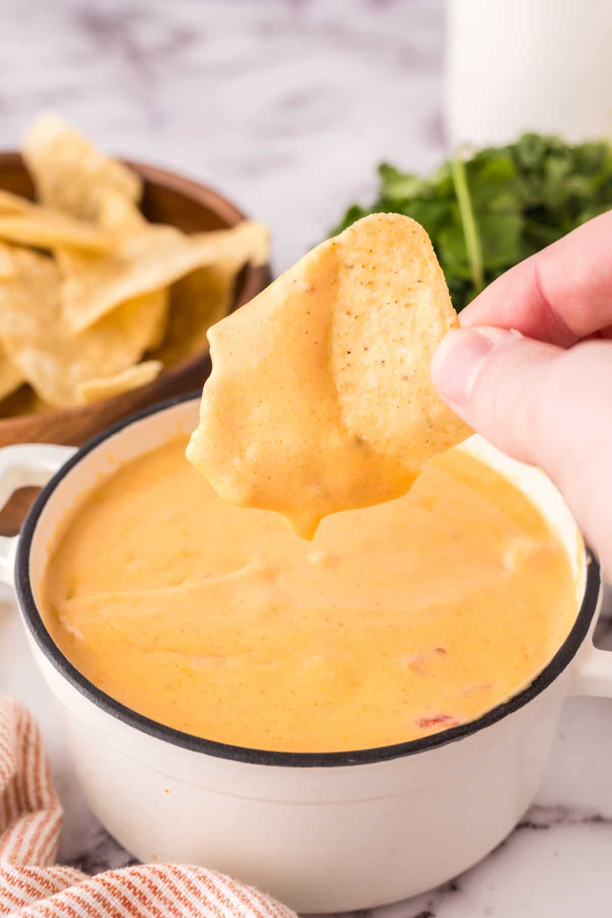 dipping a chip in the queso sauce. 