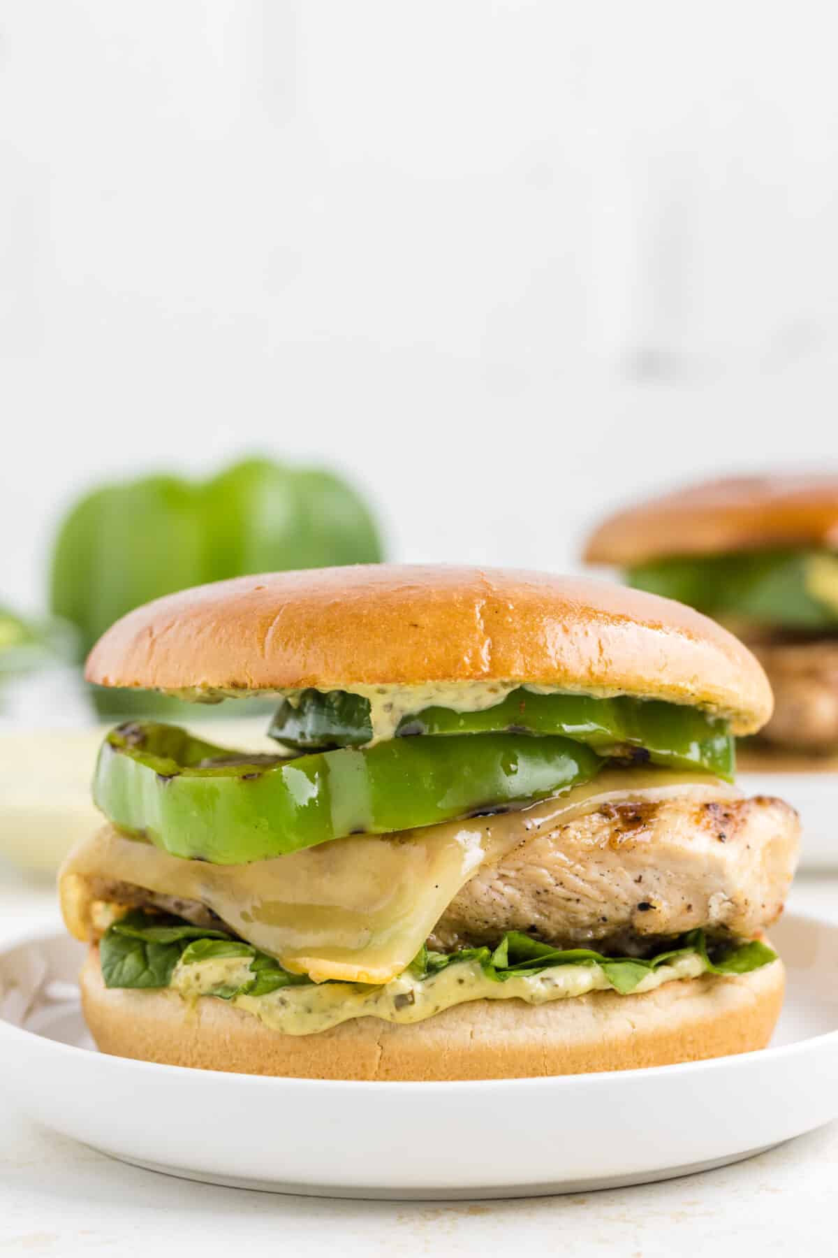 finished grilled chicken sandwich with grilled bell pepper and basil pesto mayo over a toasted bun.