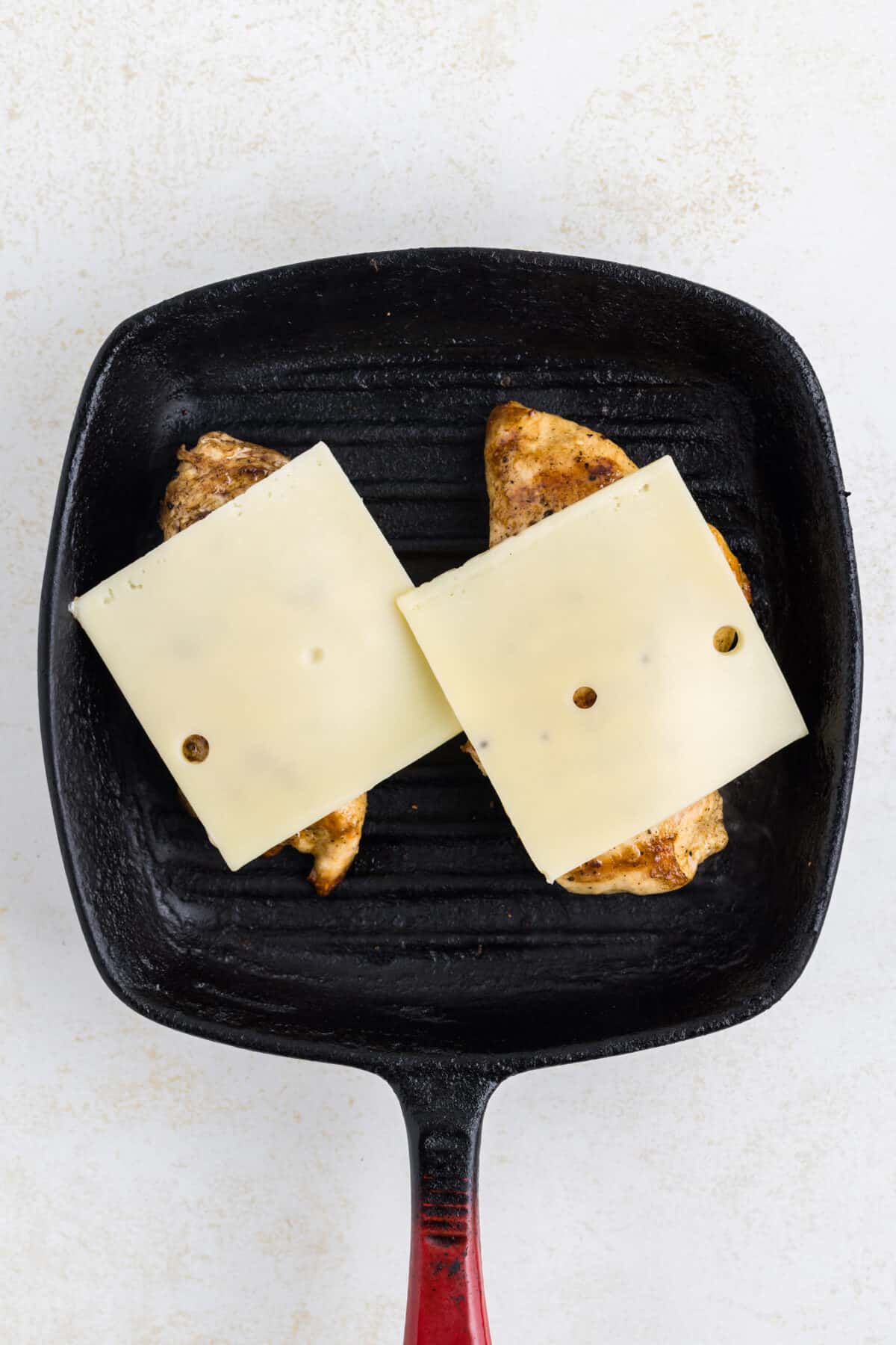 slices of Swiss cheese on the cooked grilled chicken for the sandwiches.