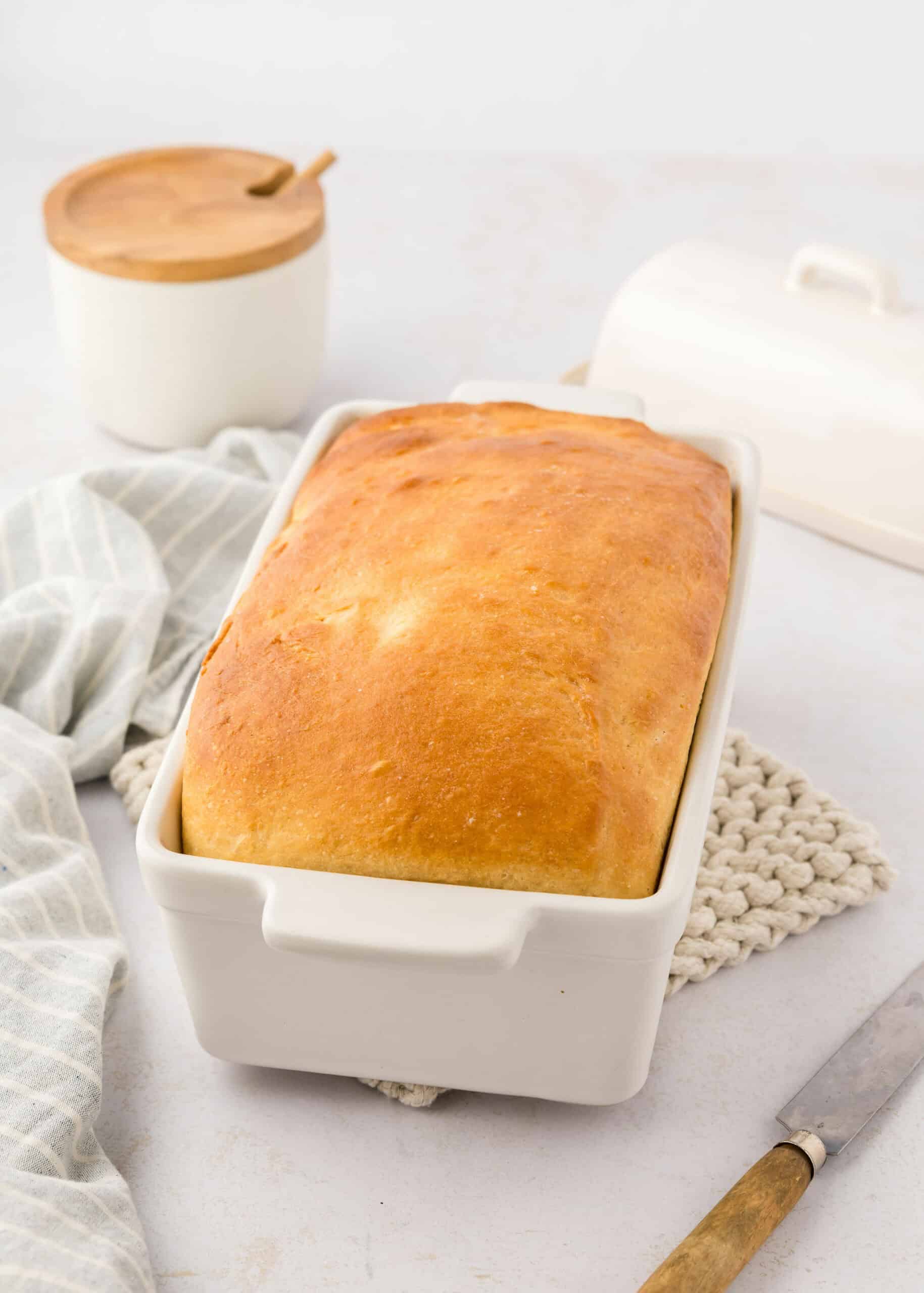 homemade sandwich bread in a white ceramic loaf pan.