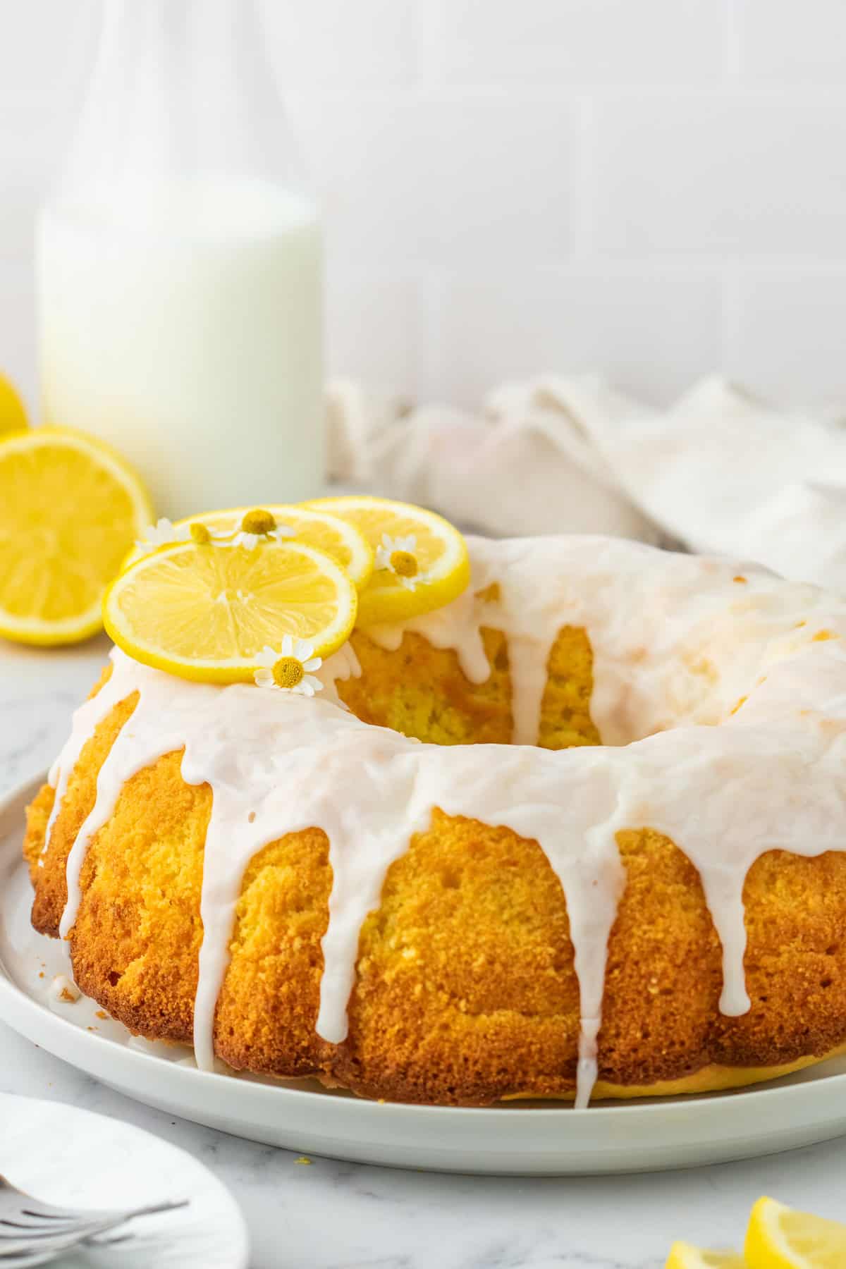 lemon bundt cake with glaze over top and on a white plate.