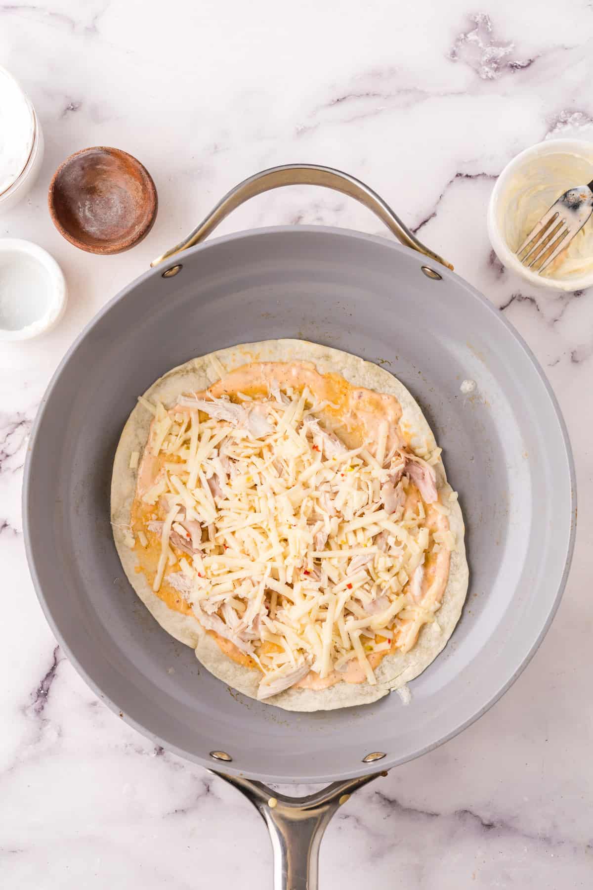 skillet with a tortilla layered with the quesadilla ingredients. 