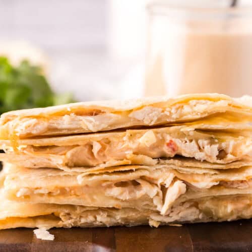 stack of chipotle chicken quesadillas on a wooden serving platter.