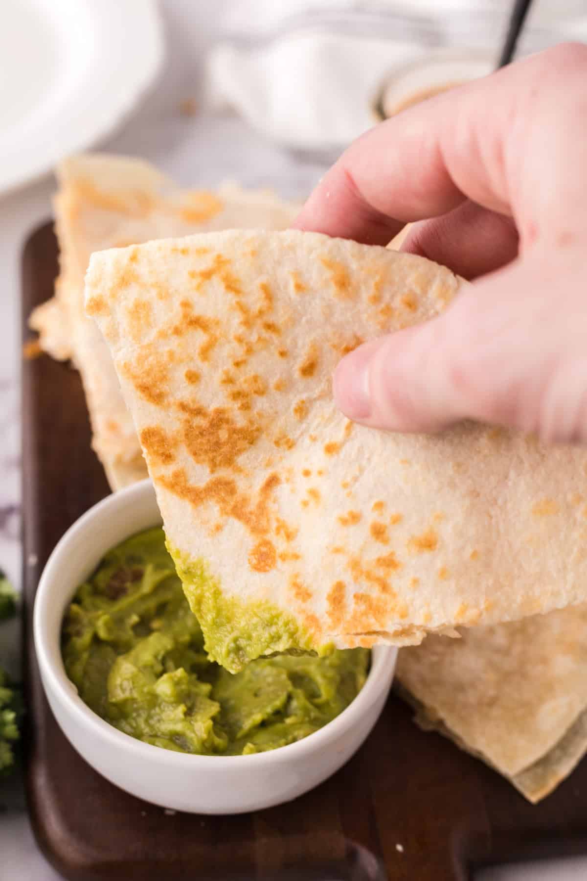 dipping the finished chicken chipotle quesadillas in guacamole. 