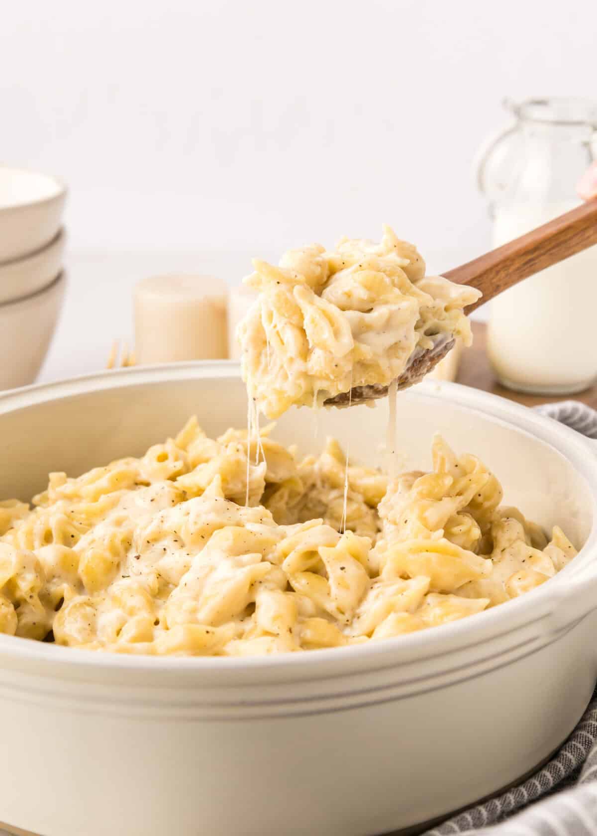 wooden spoon lifting the Mac and cheese out of the pot. 