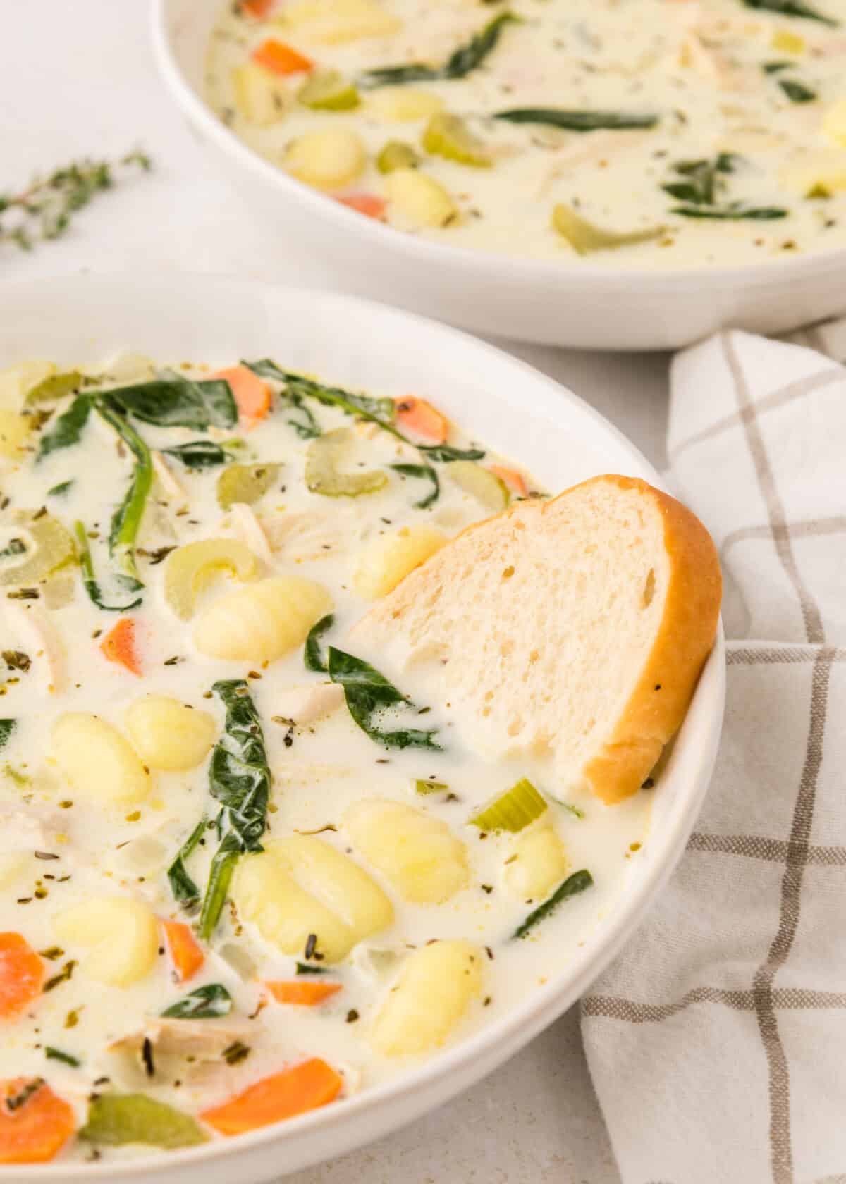 large white bowl with creamy soup and a slice bread to the side. 