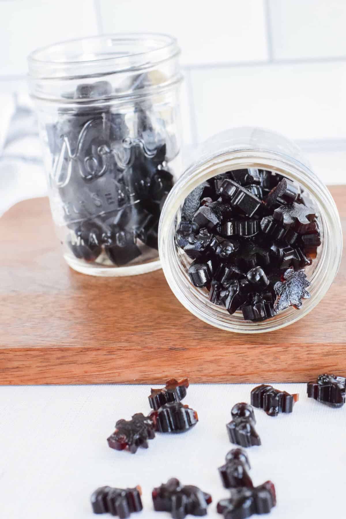 mason jars with elderberry gummies and spilled over to the table top. 